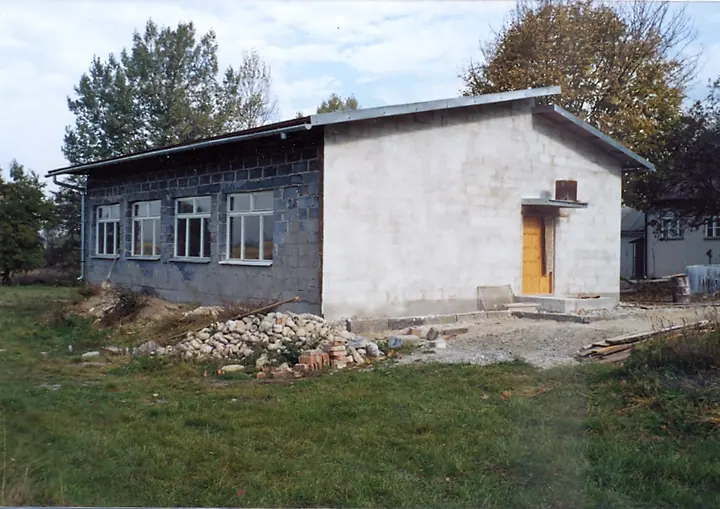 Budowa niewielkiego budynku przy szkole: wykopy, materiały, pracujący mieszkańcy.